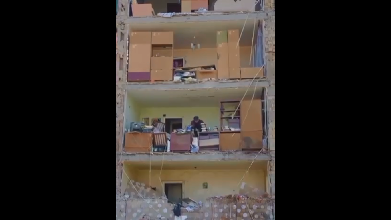 یکی از ساکنان کیئف وسایل آپارتمان خود را پس از حمله موشکی جمع آوری می کند
